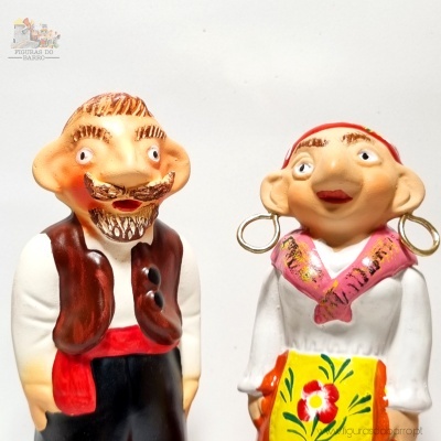 Casal em figura de cerâmica com roupas tradicionais coloridas e avental com flor