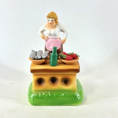 Figura decorativa de vendedora com produtos numa bancada colorida