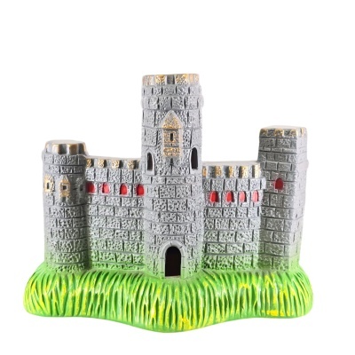 Miniatura de castelo cinza com detalhes dourados e janelas vermelhas numa base verde de relva