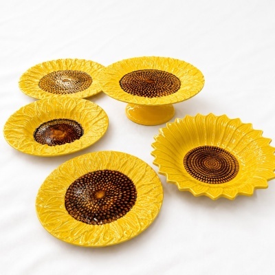 Conjunto de pratos cerâmicos decorativos amarelos com detalhes castanhos em formato de girassol.