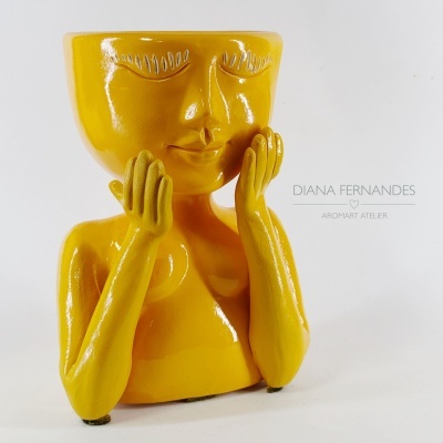 Vaso decorativo amarelo em cerâmica formato rosto humano com mãos nas bochechas