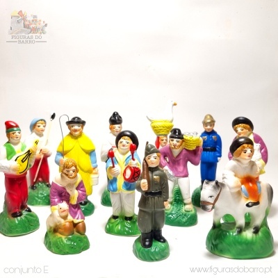 Figuras de barro coloridas de personagens tradicionais com instrumentos e criança em burro sobre base verde