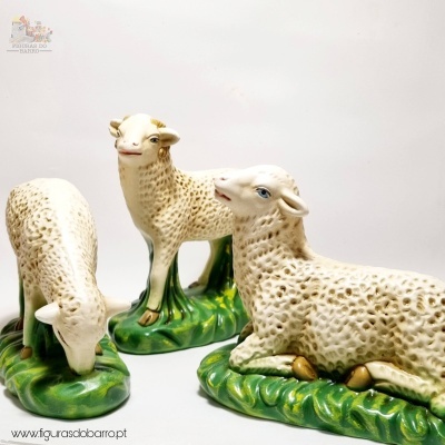 Três figuras decorativas de ovelhas em cerâmica com base verde