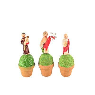 Três figuras religiosas em miniatura sobre bolas verdes em vasos