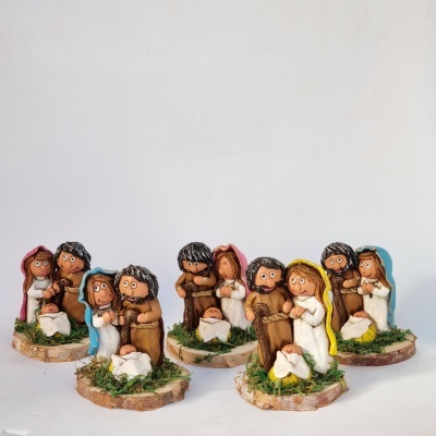 Cinco pequenas figuras de presépio em cerâmica ou resina com cores variadas e base com musgo verde.