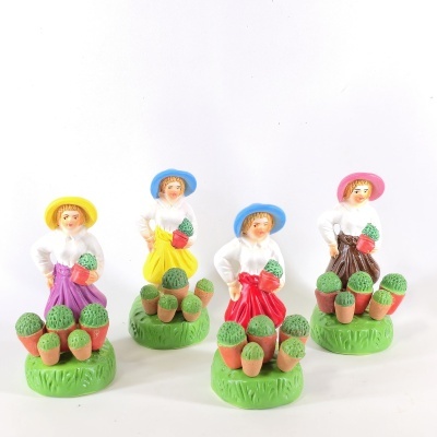 Figuras de cerâmica de mulheres com chapéus e saias coloridas a segurar vasos de plantas verdes