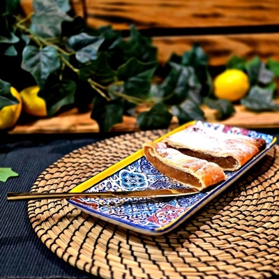 Dois pedaços de pastel de massa folhada com recheio em prato colorido sobre base de palha.