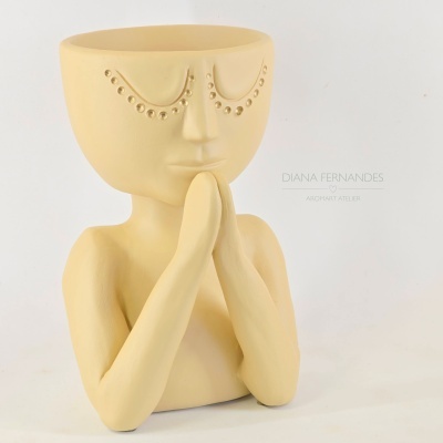 Vaso cerâmico amarelo com formato de rosto e mãos em prece