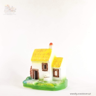 Figura decorativa de casa branca com telhado amarelo e base verde