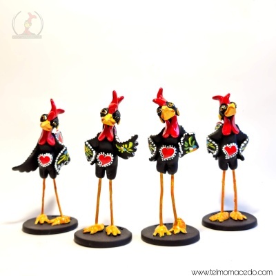 Quatro estatuetas metálicas de galos decorativos com corações vermelhos