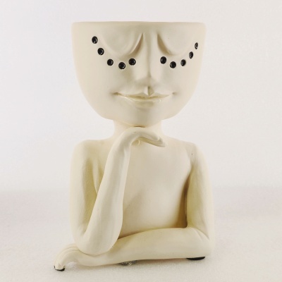 Vaso decorativo em cerâmica creme com braços cruzados e olhos em pontos negros.