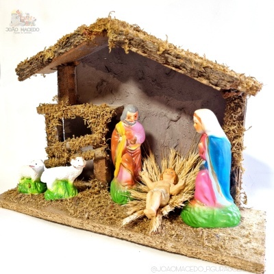 Presepe tradicional com estábulo, figuras de Jesus bebé, Maria e José, e duas ovelhas.