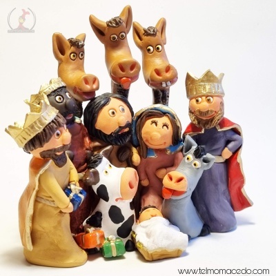 Figuras de presépio em cerâmica colorida com reis magos, sagrada família e animais sobre fundo branco