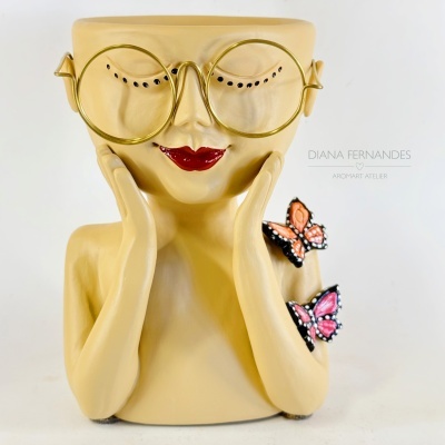 Vaso cerâmico em forma de rosto sorridente com óculos dourados e borboletas decorativas