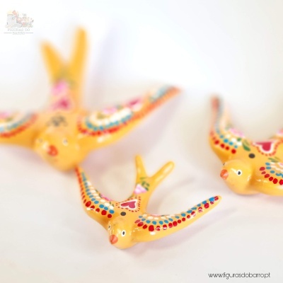 Figuras decorativas de pássaros amarelos com padrões coloridos pintados