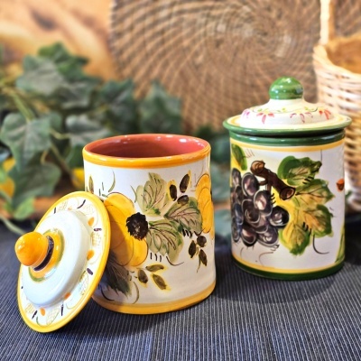 Frascos de cerâmica decorados à mão com flores e uvas em superfície cinza