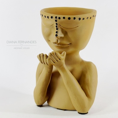 vaso cerâmico bege em forma de figura humana com detalhes pretos na testa