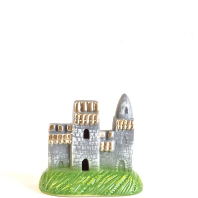 Miniatura de castelo cinzento e dourado com base verde
