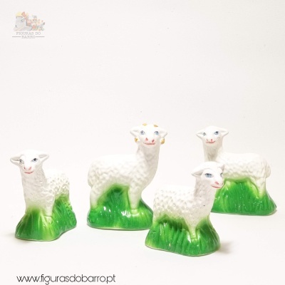 Quatro figuras de ovelhas brancas com base verde em cerâmica