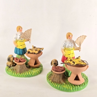 Figuras decorativas de mulheres a assar carne e salsichas com cães ao lado