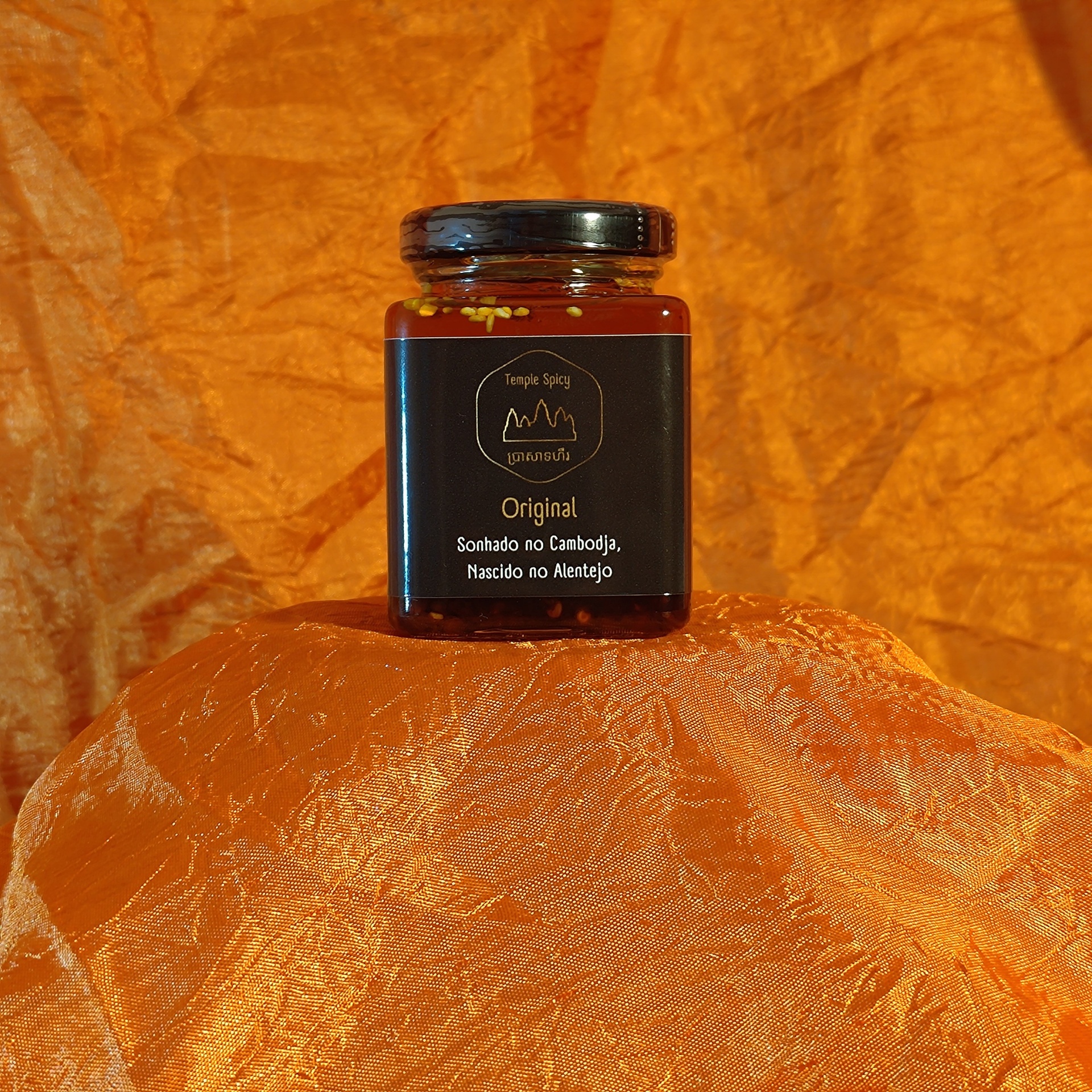 Temple Spicy Original 100ml - Molho Picante Frasco de vidro preto com rótulo preto e texto branco sobre tecido laranja