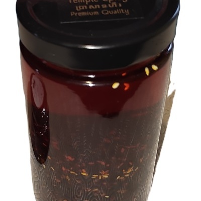 Frasco de vidro com molho vermelho e tampa preta com texto Temple Spicy.