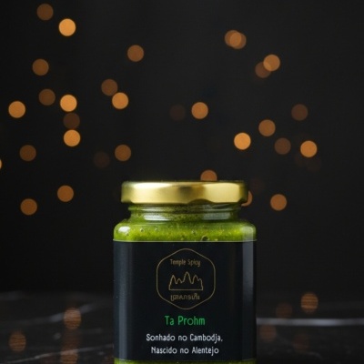 Frasco com molho verde e rótulo preto com texto em português e dourado