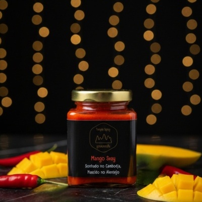 Frasco de molho Mango Svay com manga e malaguetas em fundo preto com luzes amarelas