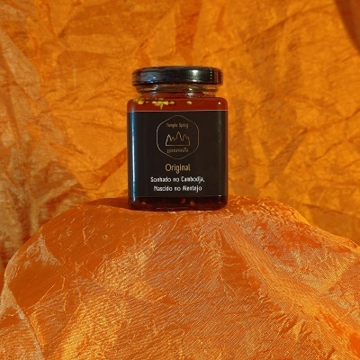 Frasco de vidro preto com rótulo preto e texto branco sobre tecido laranja