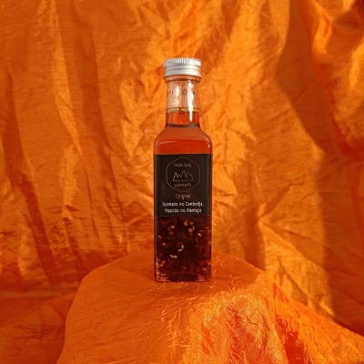 Garrafa de vidro com líquido âmbar e especiarias sobre fundo laranja