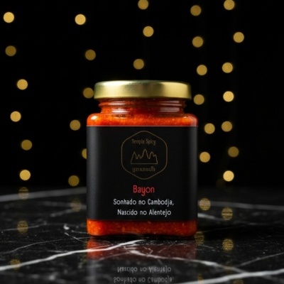 Frasco de pasta vermelha com tampa dourada e etiqueta preta com texto em fundo preto iluminado