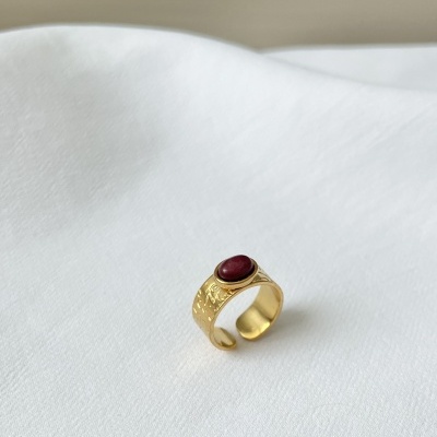 Anel dourado com pedra vermelha sobre tecido branco