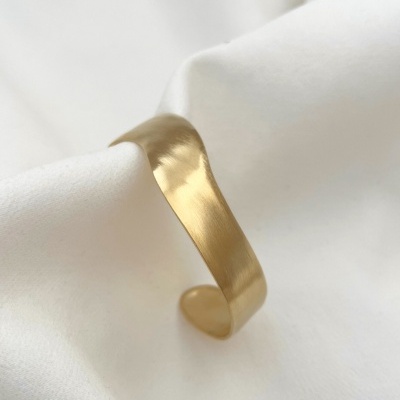 Pulseira dourada suave sobre tecido branco