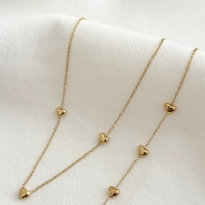 Colar dourado com corações em fundo branco
