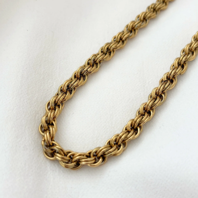 Colar dourado com corrente trançada sobre tecido branco