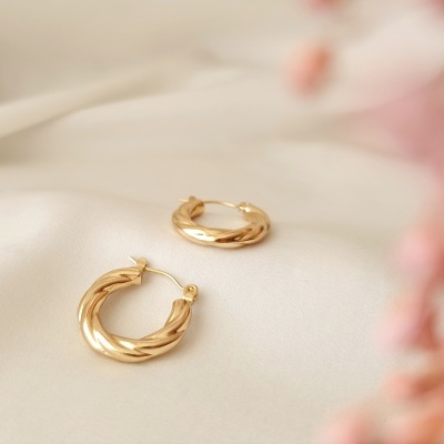 Brincos de argola dourados torcidos sobre tecido branco