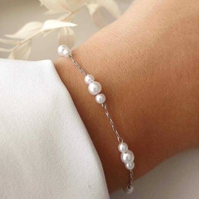 Pulseira fina com pérolas brancas no pulso