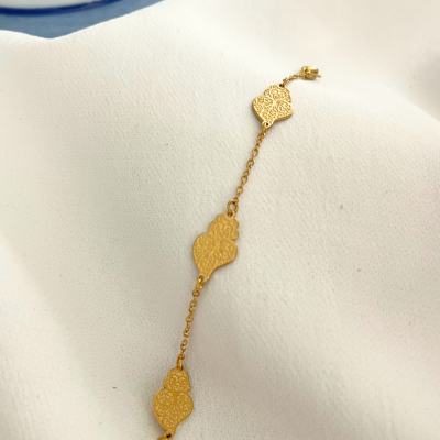 Pulseira dourada com pendentes em coração sobre tecido branco