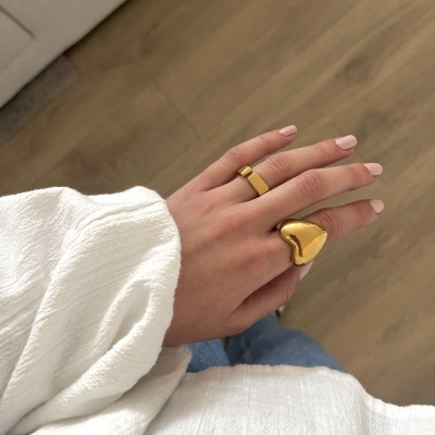 Mão feminina com anéis dourados e roupa branca