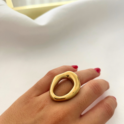 Anel dourado com design orgânico num dedo com unhas vermelhas.