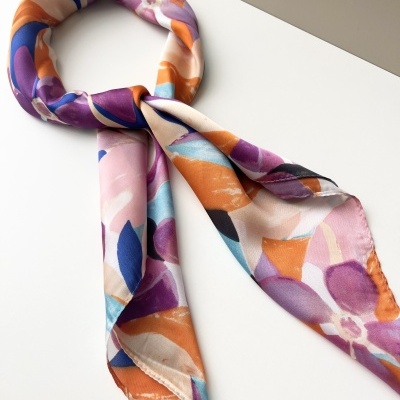 Lenço colorido com padrão floral abstrato e cores laranja, roxo, azul e bege