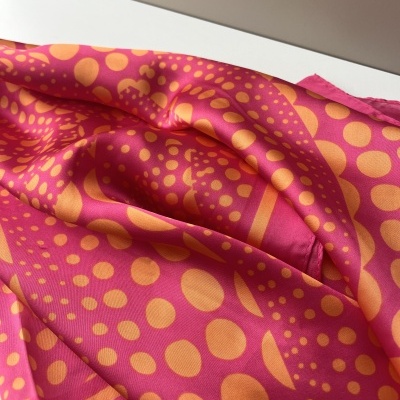 Tecido rosa com padrão geométrico laranja dobrado