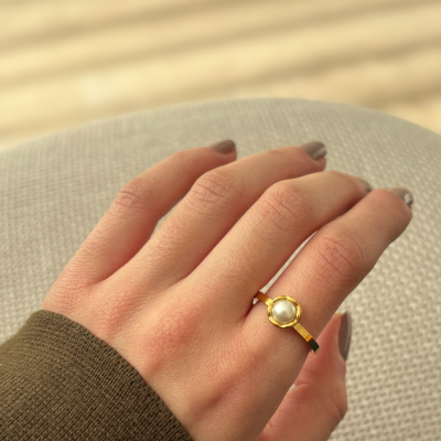 Anel dourado com pérola no dedo anelar