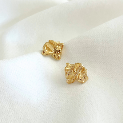 Brincos dourados texturizados sobre tecido branco