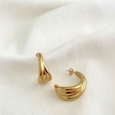 Brincos de argola dourados sobre tecido branco