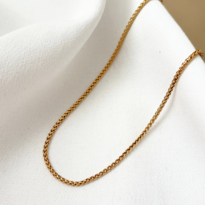 Corrente dourada entrelaçada sobre tecido branco