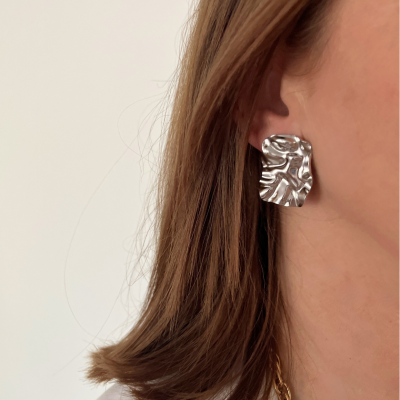 Brinco prateado ondulado numa orelha