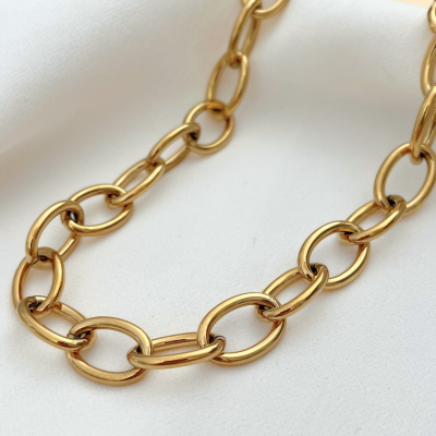 Colar dourado com elos ovais sobre tecido branco