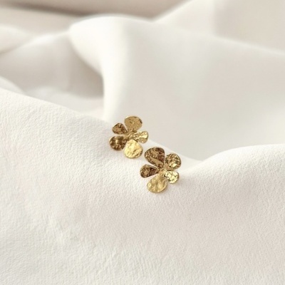 Brincos dourados em forma de flor sobre tecido branco