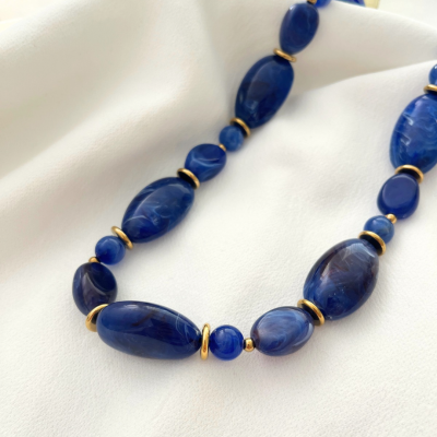 Colar azul com anéis dourados sobre tecido branco